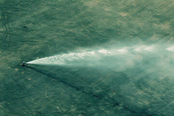Aerial view of a sprinkler irrigating a dry field.

 - obrazy, fototapety, plakaty