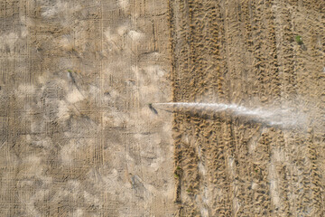 Aerial view of a sprinkler irrigating a dry field.

 - obrazy, fototapety, plakaty