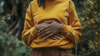 Fototapeta premium A person holding their abdomen with a pained expression, depicting symptoms of stomach ache or cramps associated with gastrointestinal issues. 