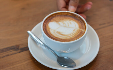 Hot latte art coffee cup on wooden table