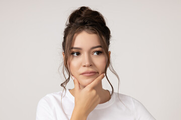 Attractive young girl is thinking on a white background
