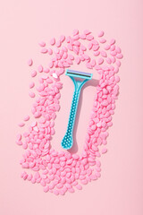 Wax granules for depilation with a razor on a pink background