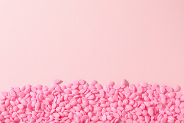 Wax granules for depilation on a pink background