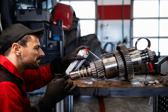 Experienced mechanic repairing and servicing transmission gears for tractor agricultural machine.