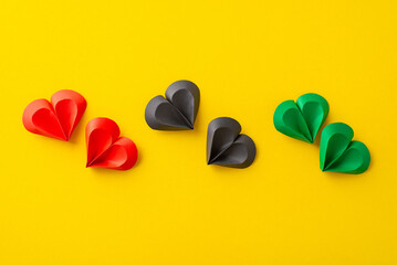 This image showcases a series of colorful paper hearts arranged in a sequence on a vivid yellow...