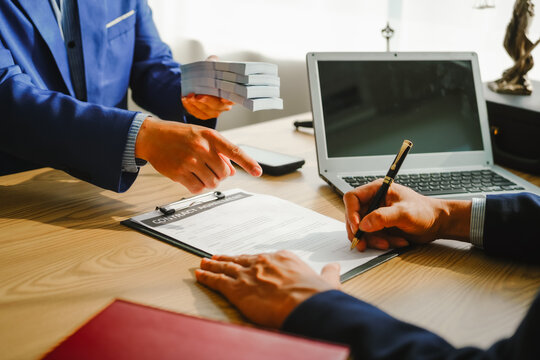 Legal expert navigating corruption cases, including bribery and graft. Businessman consults at desk. Discussions involve bribery, corruption, buying off, and corrupt practices.