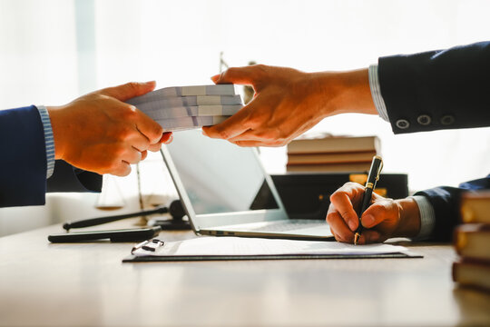 Legal expert navigating corruption cases, including bribery and graft. Businessman consults at desk. Discussions involve bribery, corruption, buying off, and corrupt practices.