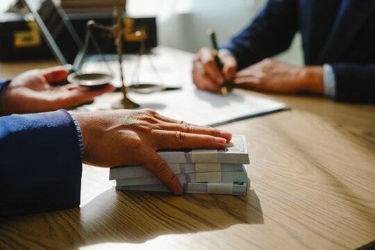 Legal expert navigating corruption cases, including bribery and graft. Businessman consults at desk. Discussions involve bribery, corruption, buying off, and corrupt practices.
