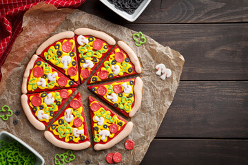 A creative display of gingerbread cookies, intricately decorated to resemble vibrant pizza slices,...