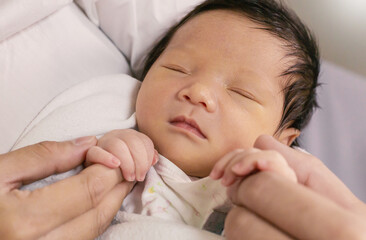 Portrait of asian parent hands holding newborn baby fingers, Closeup mother’s hand holding their...