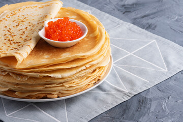 Pancakes with red caviar on grey background, with copy space for text