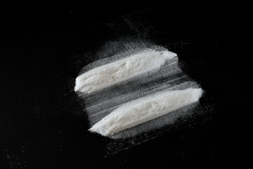 White powder lies in two stripes on a black background.
