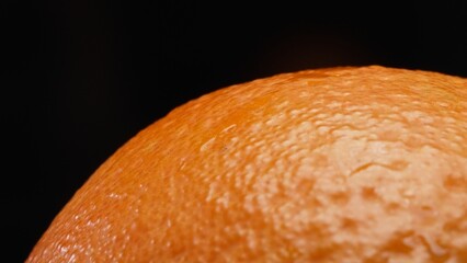 Macrography, the intricate texture of an orange against a striking black background steals the...