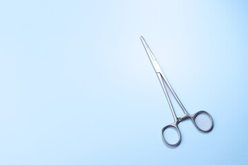 A pair of scissors is on a blue background. The scissors are silver and have a pointed tip. Concept...