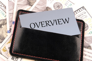 OVERVIEW written on a business card in a leather accessory on the background of banknotes