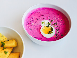 A bowl of popular Lithuanian cold beetroot soup Saltibarsciai with baked potato wedges