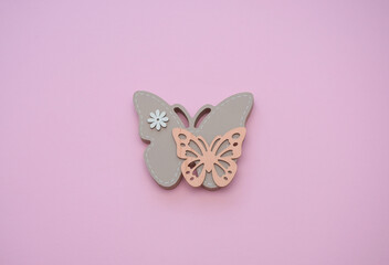 Wooden butterfly on a pink background. Top view. Flat lay.