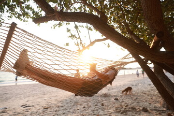 Selective focus on the girl on the white hammock and the shadow on a sandy beach on a sunny day, a family vacation concept.