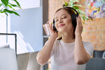 Young happy woman in headphones with closed eyes enjoying music, audio book