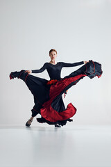 Passionate essence of flamenco dance. Artistic woman performing dynamic pose dancing against grey...