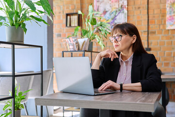 Middle-aged business woman working remotely with laptop in coworking