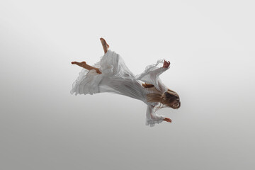 Woman dressed in vintage white gown suspend in mid-air, her long blonde hair cascading around her...