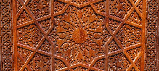 Arabic Uzbek Islamic patterns arabesque ornament on an brown wooden carved door in Uzbekistan close up