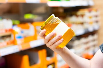 The guy in the supermarket holds a glass jar of honey