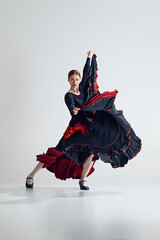 Grace and passion. Elegant woman in striking black and red dress making powerful flamenco dance...
