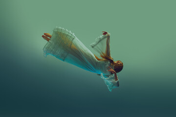 Woman in white vintage dress falls slowly through serene aqua background, evoking sense of weightless descent. Concept of beauty, elegance, mystery and depth, weightlessness. Ad