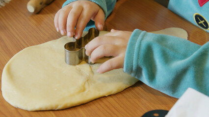 Child using gingerbread man cookie cutter and making christmas cookies. High quality photo