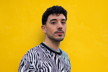 Young man in zebra print shirt posing against a bright yellow background