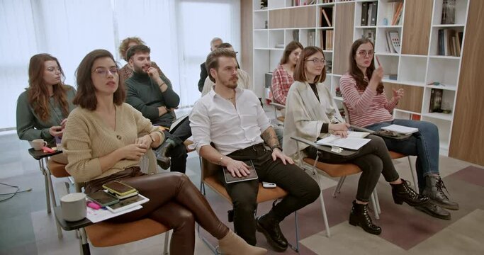 In a office classroom, a cross-generational group of business employees participates in a corporate business training or seminar, highlighting the importance of continuous learning and development.