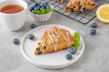 Blueberry scones with lemon glaze on top on a gray concrete background. Delicious breakfast.