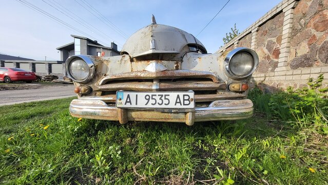 Nice old rusty soviet car Volga on green grass near the building at sunny evening, april 2024 Ukraine