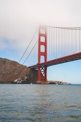 Fototapeta premium Discover the mesmerizing Golden Gate Bridge in San Francisco, California. Captured from water level, this iconic landmark stands tall with vibrant red orange against a calm blue sky.