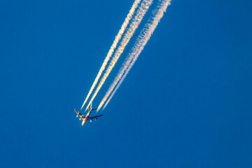 Ein Großraumflugzeug in der Abendsonne auf Reiseflughöhe mit dem vier Kondensstreifen hinter...