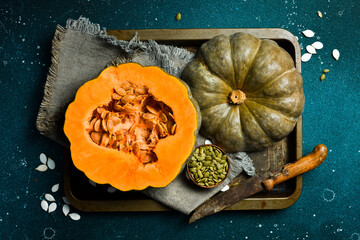 Organic pumpkin cut in half with seeds. Orange green skinned pumpkin. Autumn vegetables. Top view.