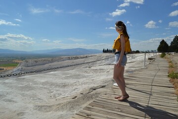 A girl standing on a rock admires nature, panorama, landscape. Travel, tourism, excursions. Turkey. Pamukkale.