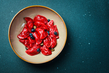 Dumplings with cherries, raspberries and salted caramel. On a black stone background. In a plate,...