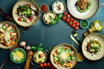 table with food, A set of food and dishes in plates. View from above. Food banner. On a dark stone...