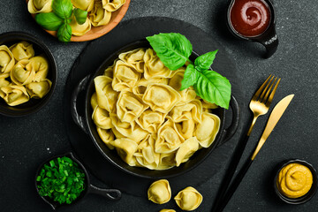 Italian traditional ravioli with meat and basil. Top view, on a dark stone background.