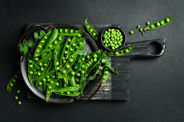 Green young peas on a dark stone background. Healthy food. Top view.