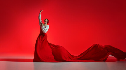 Intensity of flamenco dance. Creative artistic performance, elegant female dancer in bright costume dancing against red background. Concept of art of movement, classical dance, beauty, festival