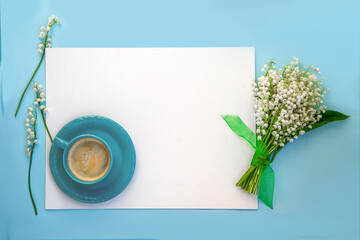 Greetings card on a blue background with a bouquet of lilies of the valley and a cup of  coffee
