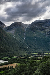 Towering Litlkalkinn mountain with a stream flowing down the mountainside towards the lush valley...