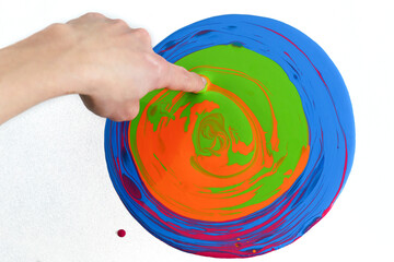 human hand with a finger touching a circle of colors and mixing them