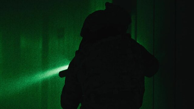 Two soldiers with guns walking down a corridor night-vision