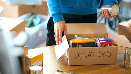 Close Up Of Male Charity Volunteer Working At Food Bank Unpacking Donations