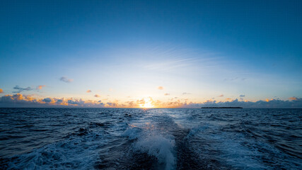 boat waves under sunset at sea - grey colours yellow sun in Maldives